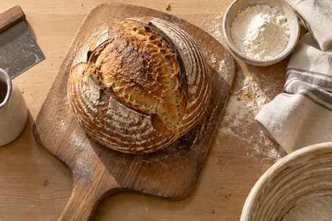Generated sourdough and a baker’s peel on a light wooden bench.