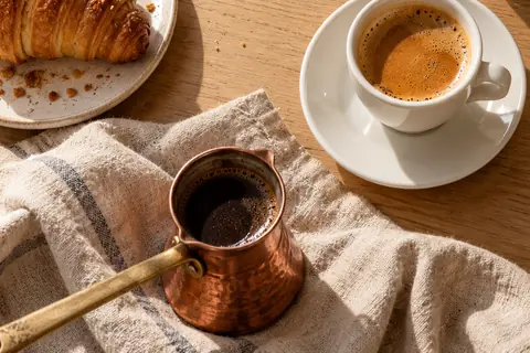Generated porcelain coffee cup beside a pastry on a morning counter.
